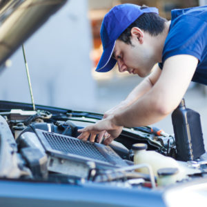 mechanic performs inspection under the car hood