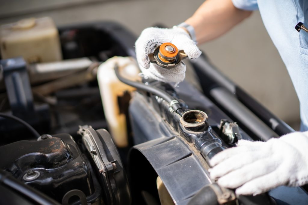 mechanic checking coolant reservoir for coolant level