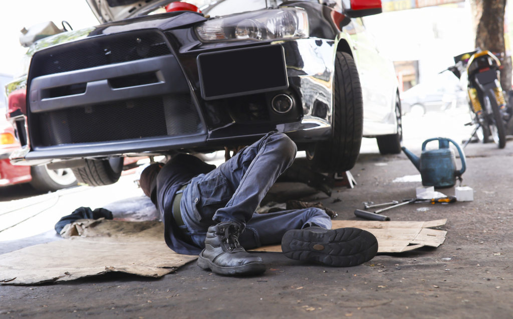 car mechanic checking underneath a car