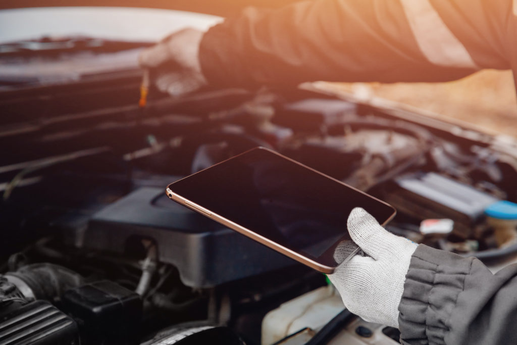 car mechanic holding a tablet while repairing car