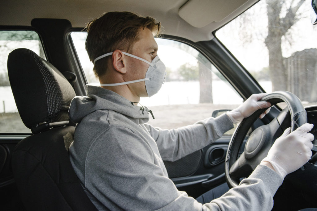 man wearing n95 respirator mask and gloves while driving
