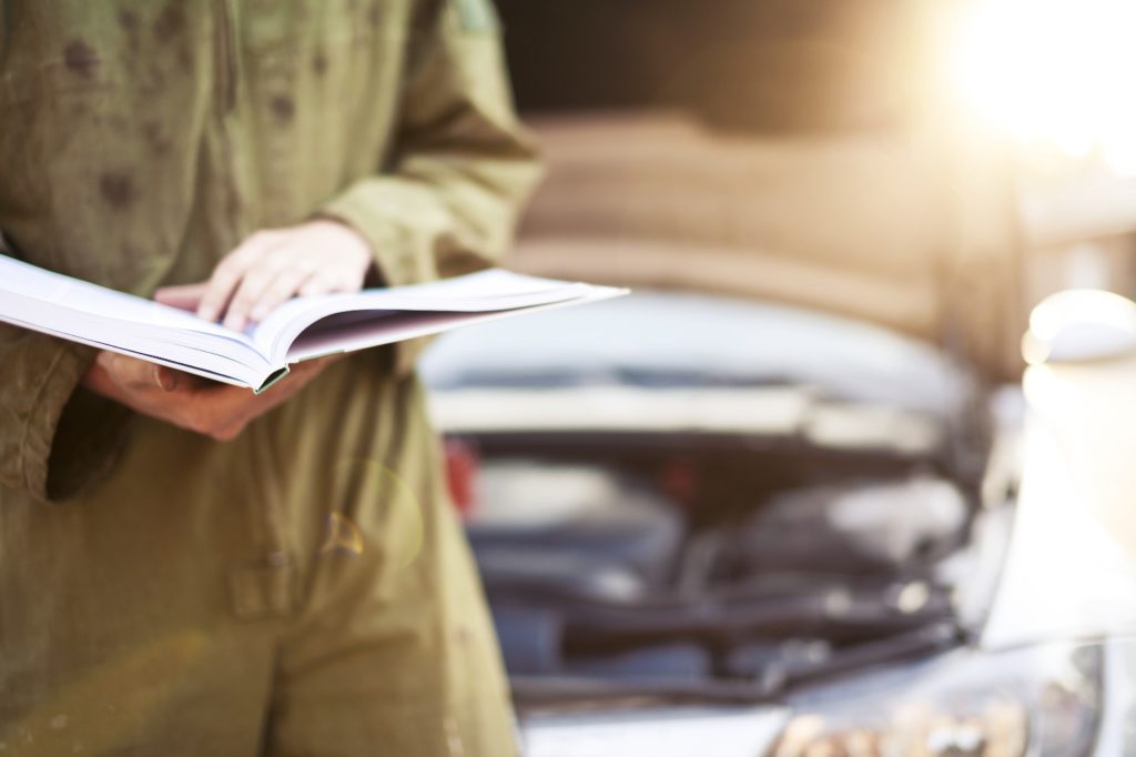 Mechanic reading instructions from car manual
