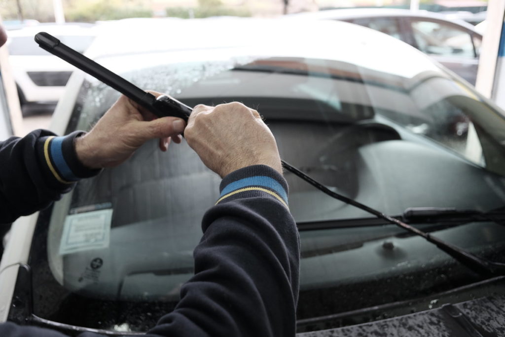 man replacing wiper blades on car