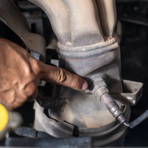 car mechanic pointing to an oxygen sensor