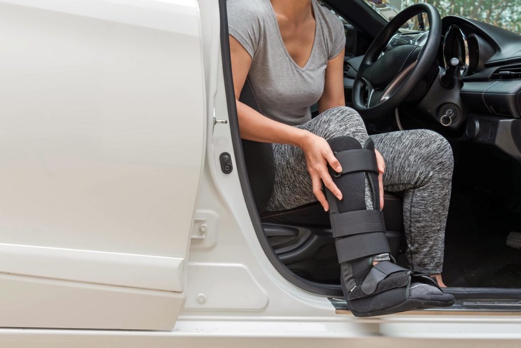 Injured woman wearing a black cast while sitting in the car