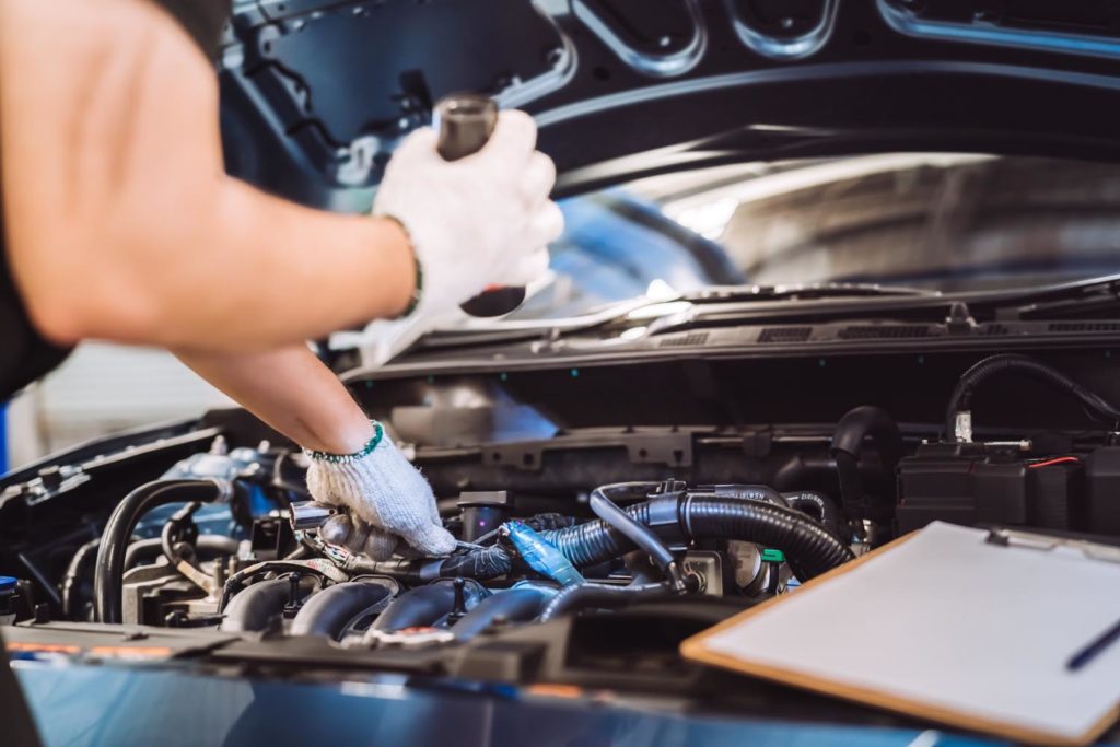 Mechanic man examining the hood of a car for maintenance