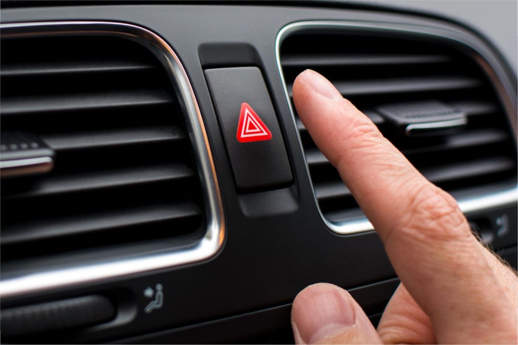 Person clicking emergency light button in car