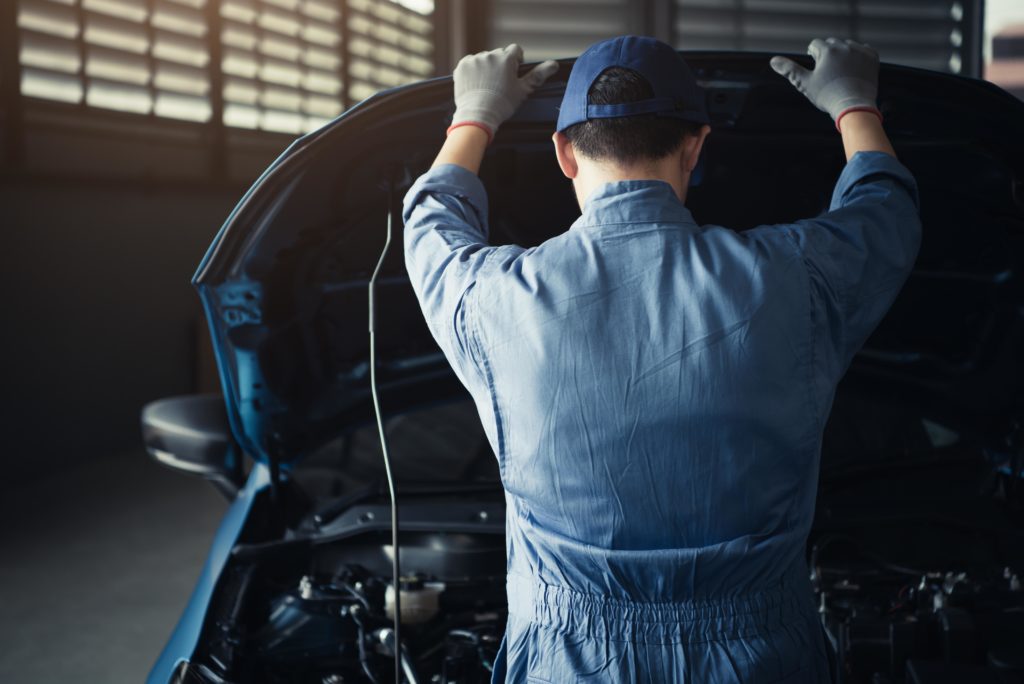 male mechanic checking car hood to look for the car PCM