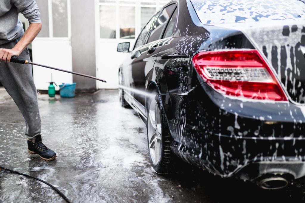 man doing car wash with high pressured water