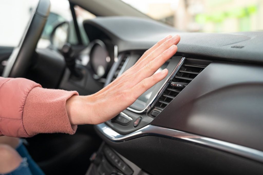 woman checking air conditioning inside the car