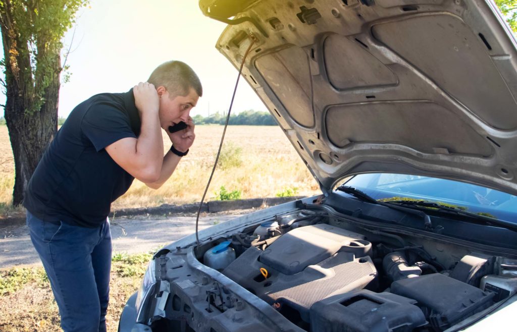 frustrated man looks at the idle car engine