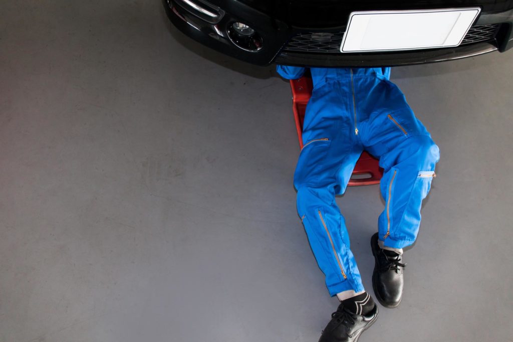 mechanic checks under the car for repair