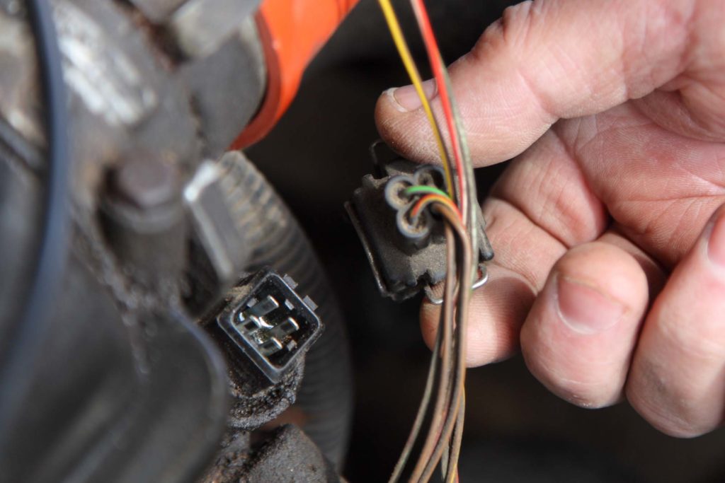 mechanic hand removes the connector from the 4 pin coolant temperature sensor