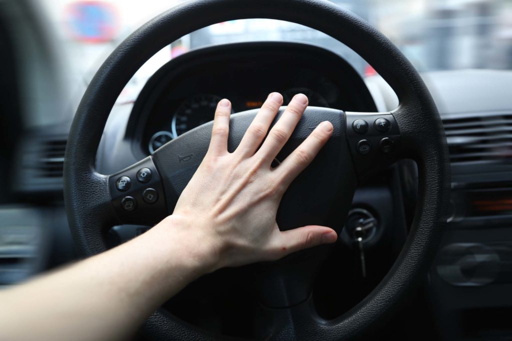 panicking hand pushing the steering wheel of a car whilst driving