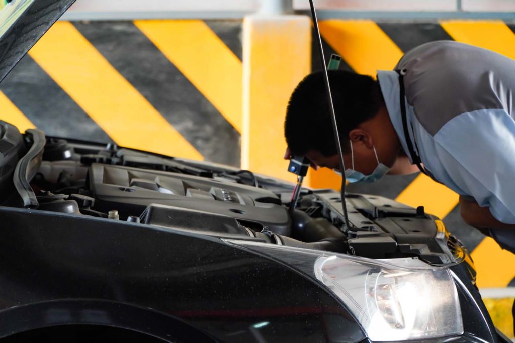 man performs car hood visual inspection