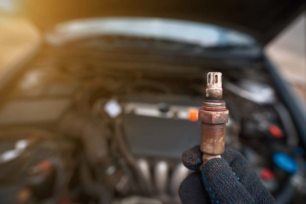 Man hold in hand faulty old oxygen sensor of exhaust system focused view