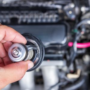 man with a car thermostat replacement part close look