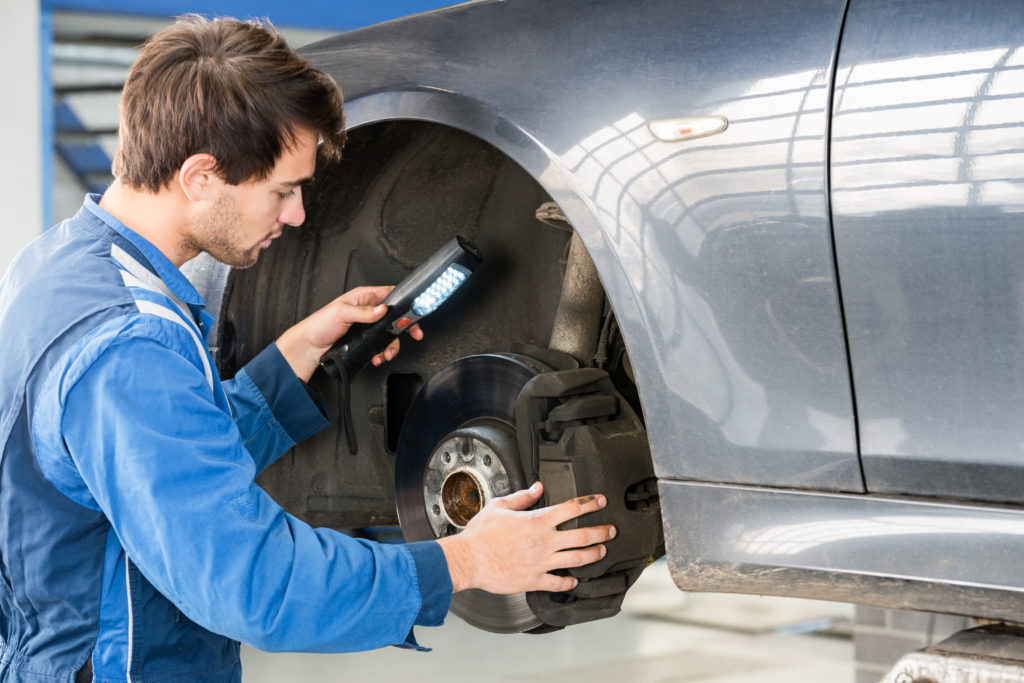 mechanic inspects new car brakes with flashlight.jpg
