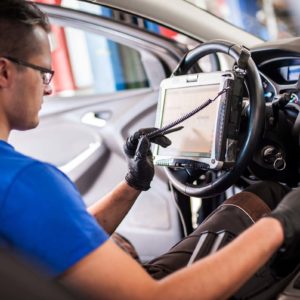 man running diagnostic equipment inside car