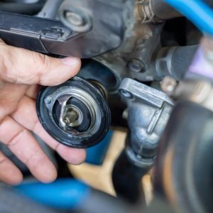 Mechanic holds a car thermostat with clear view