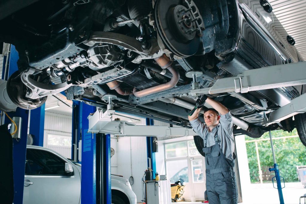 mechanic inspecting the underside of a vehicle