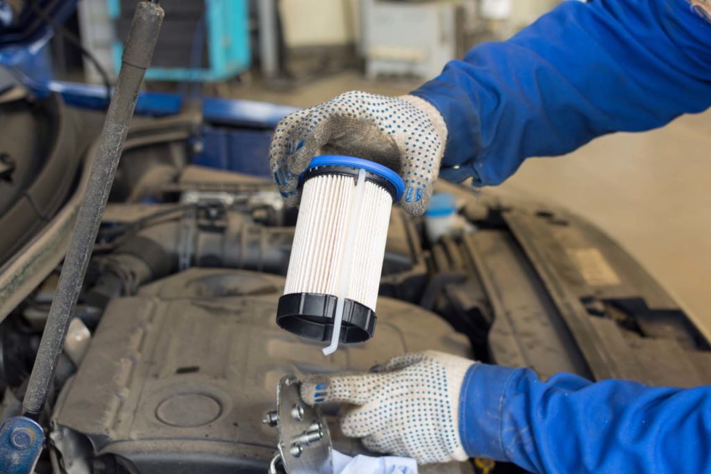 mechanic is holding a new engine fuel filter for replacement
