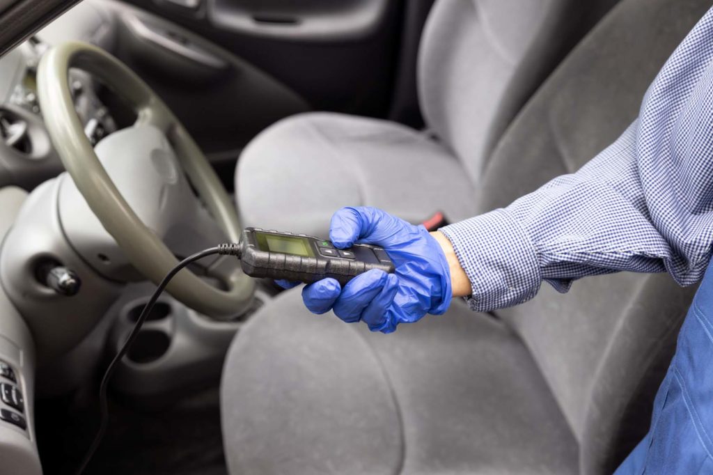 auto mechanic using diagnostic scan tool inside the car