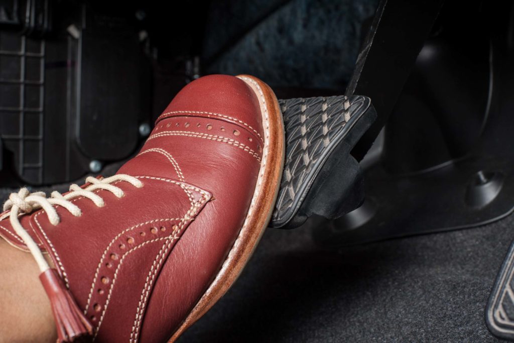 car brake pedal pressed by brown shoe