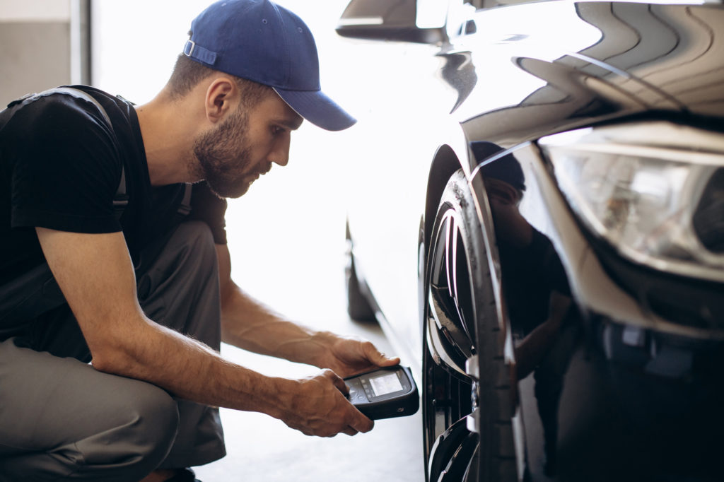 male checking tire pressure sensors with a tool
