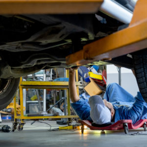 mechanic checking car undercarriage to reach exhaust pressure control valve