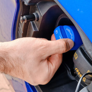 man removing cap to pour diesel exhaust fluid