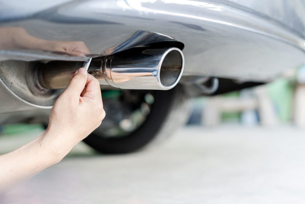hand fixing an automotive muffler