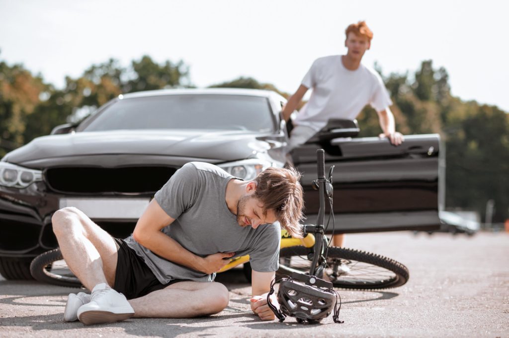 cyclist on pavement after getting hit by a car
