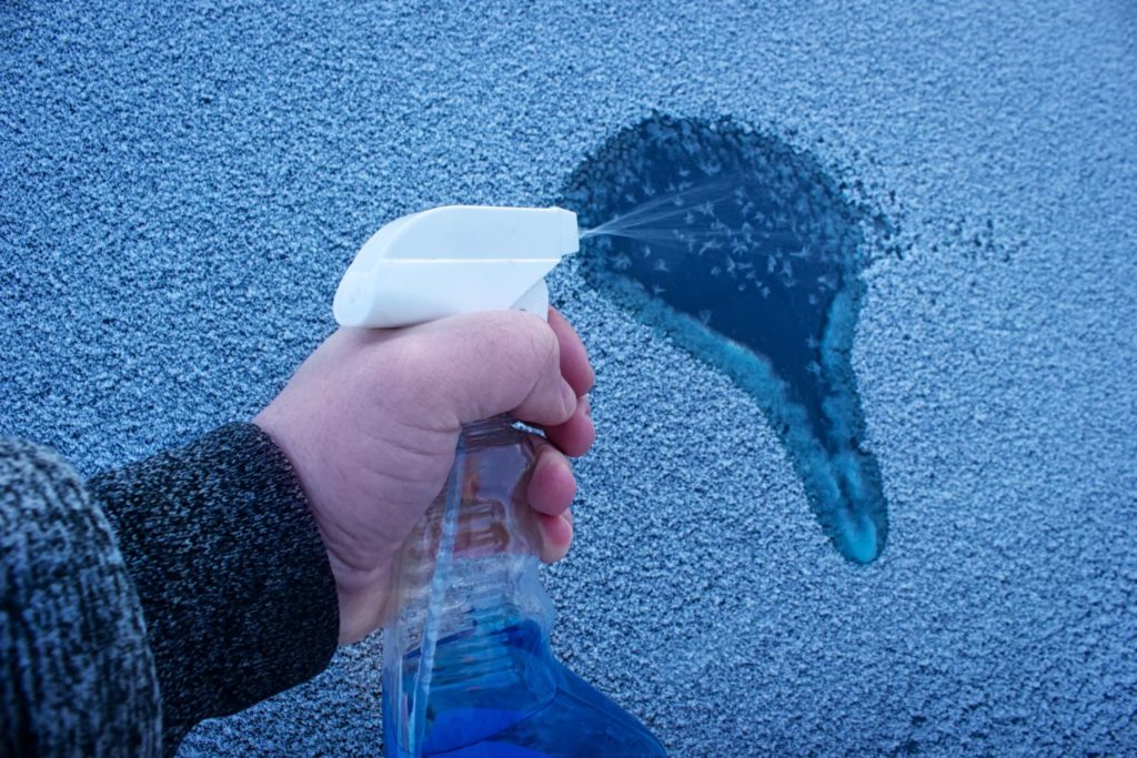 spraying deicing solution to a frozen car window