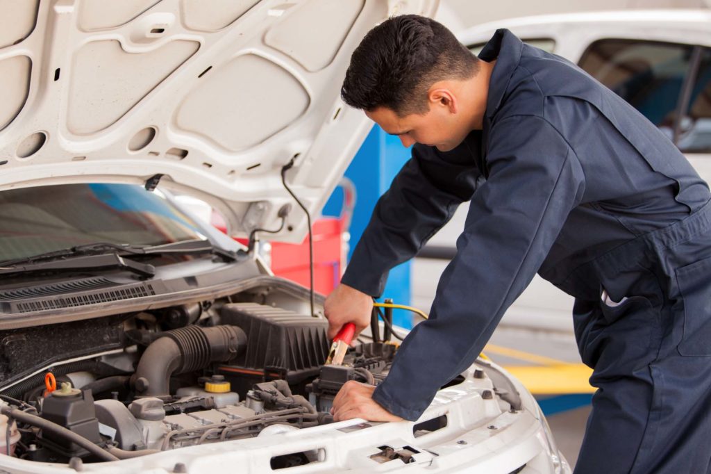 male mechanic jump starts a car battery