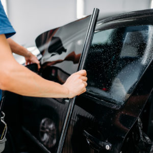 specialist applying car tint film on black car