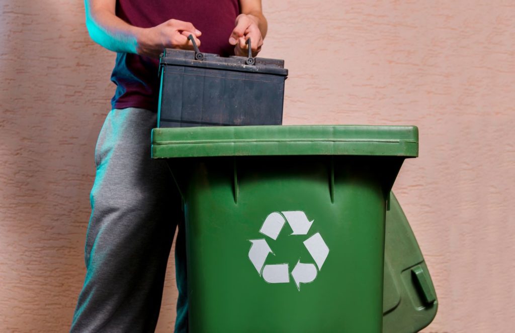 throwing old car battery in a hazardous waste bin
