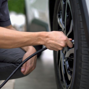 man putting air on car tire close up