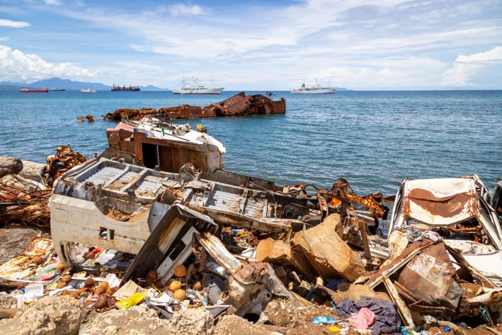 wrecked cars and garbages beside an ocean