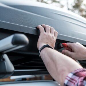 man putting keys in a car trunk lock