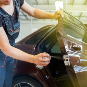 woman spraying lubricant to a car door latch