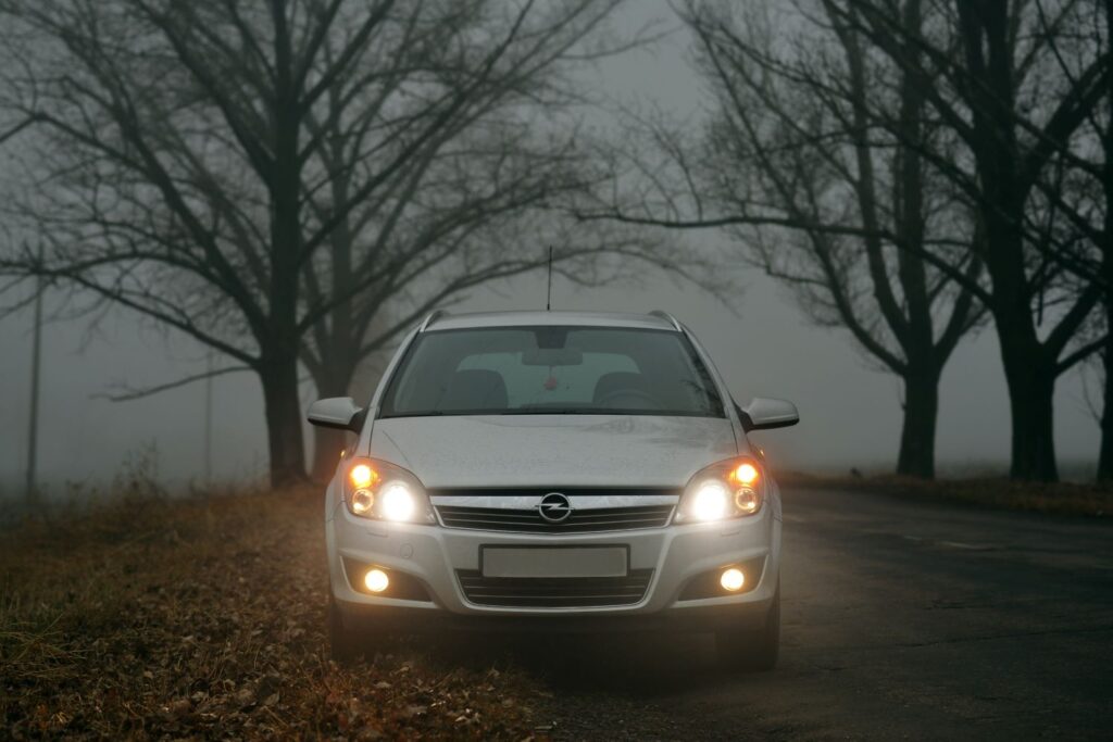parked white car with hazard and turn signal lights on