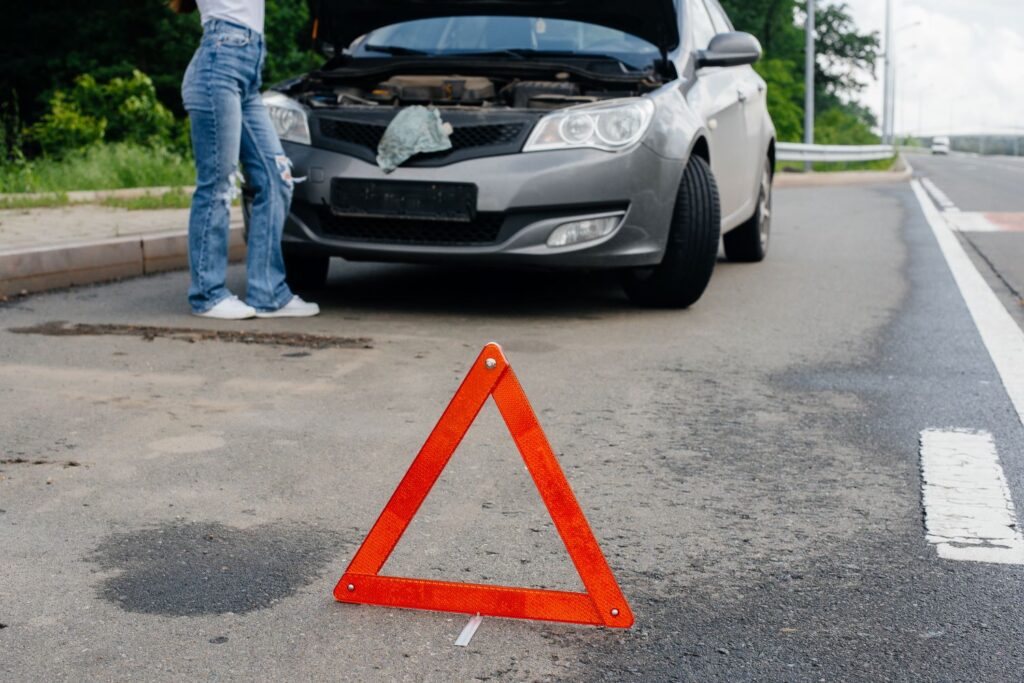 car stalled on a highway with a hazard road sign