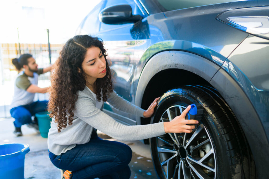 young woman cleaning car tires