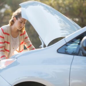 woman checking the engine of a white car