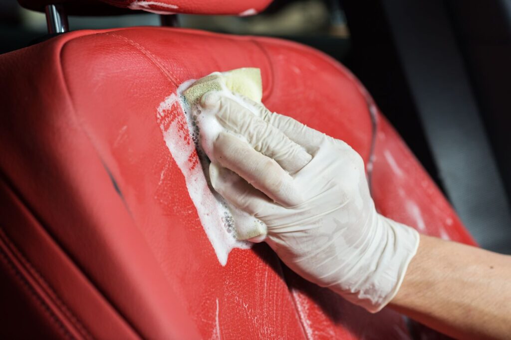 cleaning red car leather seat using foam and soap