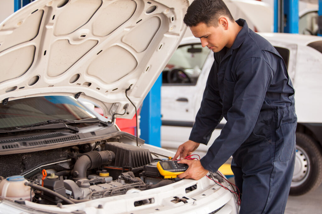 Young,Mechanic,Checking,The,Voltage,Of,A,Battery,Using,A