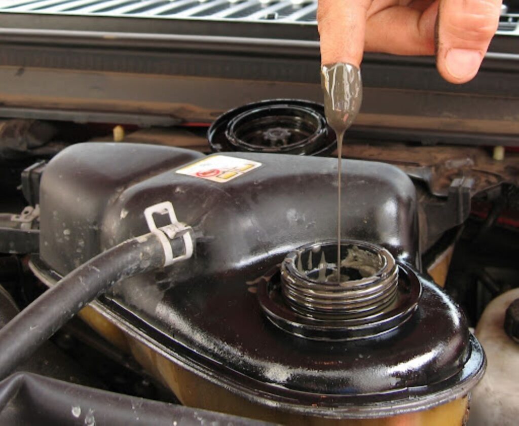 mechanic showing oil from the coolant reservoir
