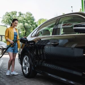 woman pumping gas in a black car