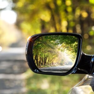 close up shot of side mirror of a parked car beside a road